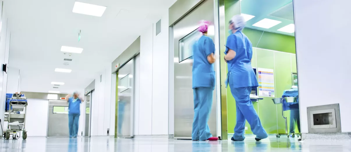 blurred figures wearing medical uniforms in hospital surgery corridor