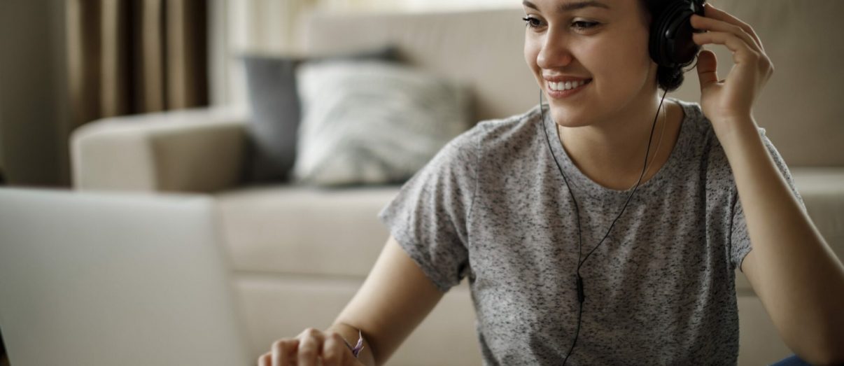 Young woman using laptop and listening to music at home