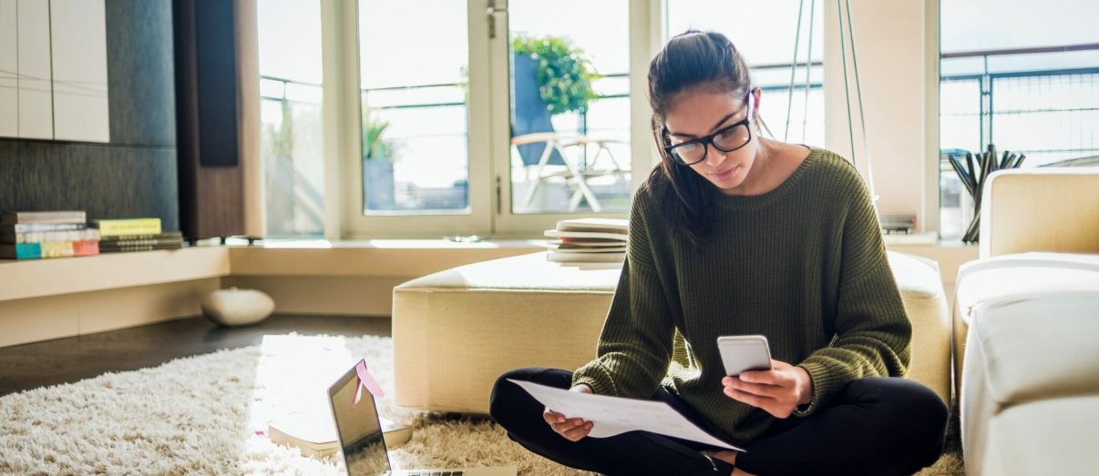 young woman sitting on the floor of her living room and working