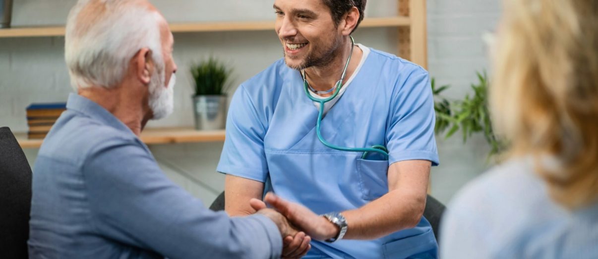 Happy doctor greeting with senior man and shaking hands with him while being in a home visit.