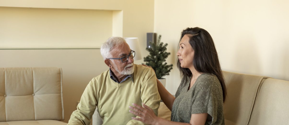Senior Man and his Beautiful Daughter are Relaxing at Home while Sitting in the Living Room of Comfortable Apartment and Talking.