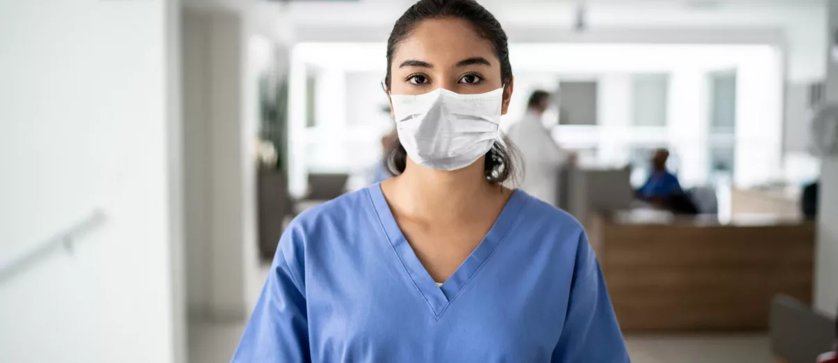 Portrait of female nurse holding digital tablet at hospital using protective mask