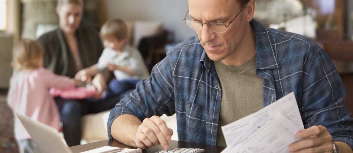 Father paying bills with family behind him